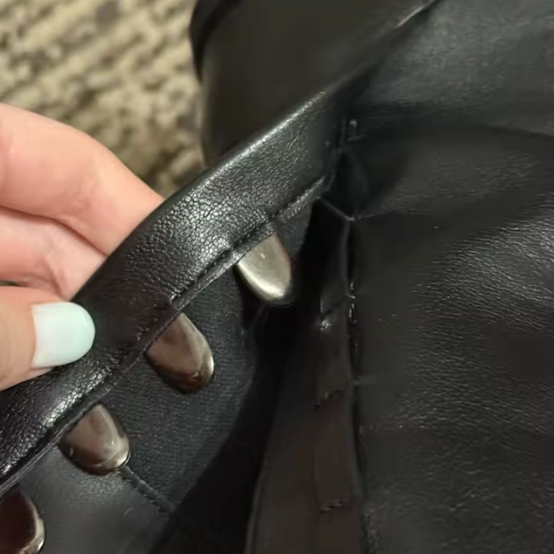  mão feminina  abrindo/fechando a alça com fivela metálica prateada, mostrando o detalhe do fechamento em couro sintetico preto. Imagem de produto em uso real, foco total no mecanismo de fechamento.