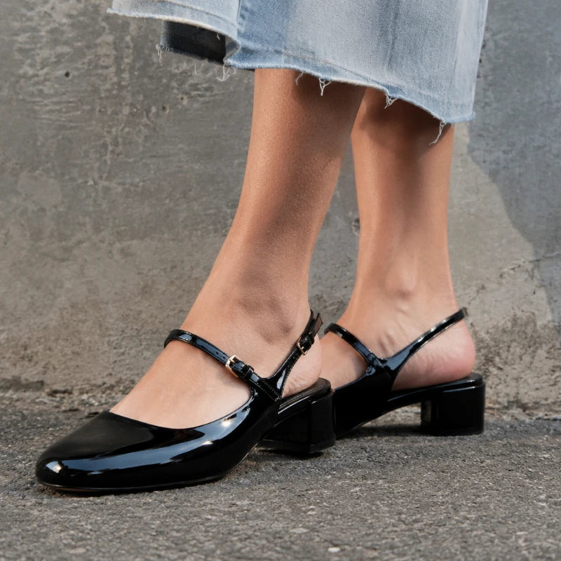 Detalhes das fivelas, tiras e acabamento brilhante do slingback preto Maelle nos pés