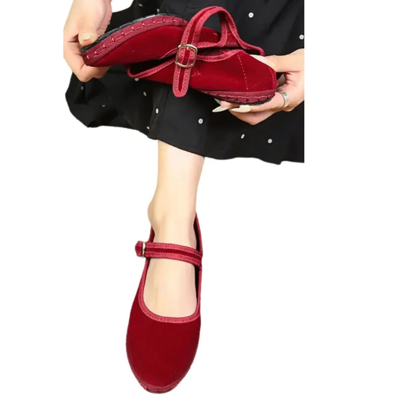 Mulher calçando sapatilha Mary Jane de veludo vermelho cherry – detalhe flexibilidade do solado  e tira com fivela