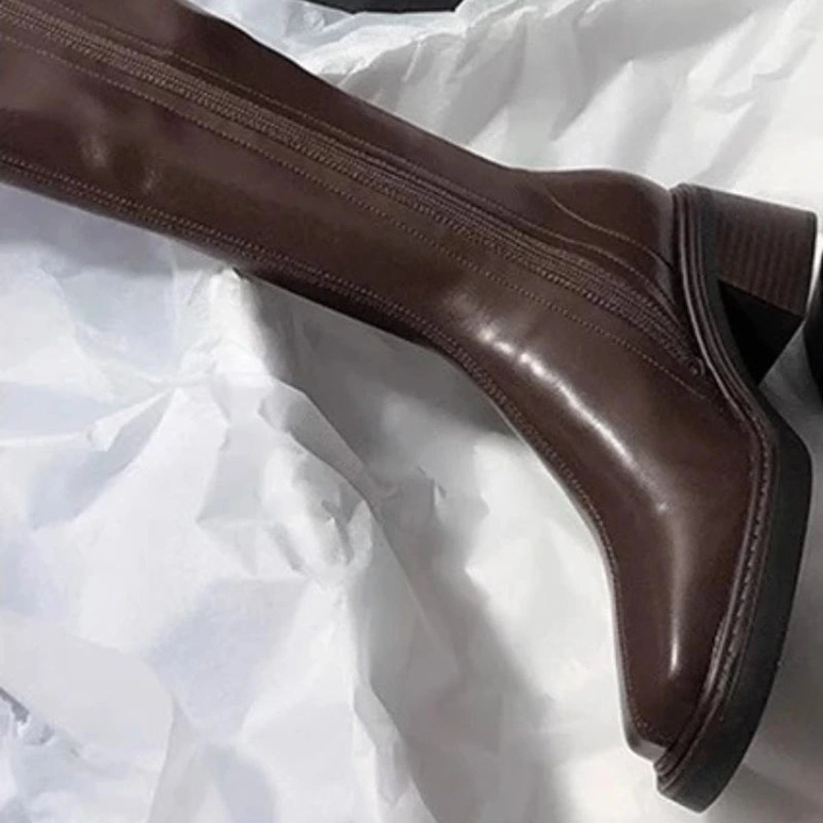 Detalhe do zíper, solado e salto grosso da bota marrom