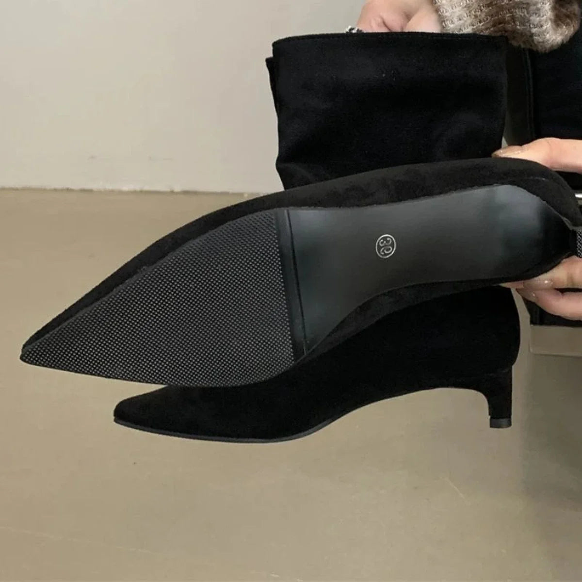 Detalhe do solado e salto baixo da bota preta Helena