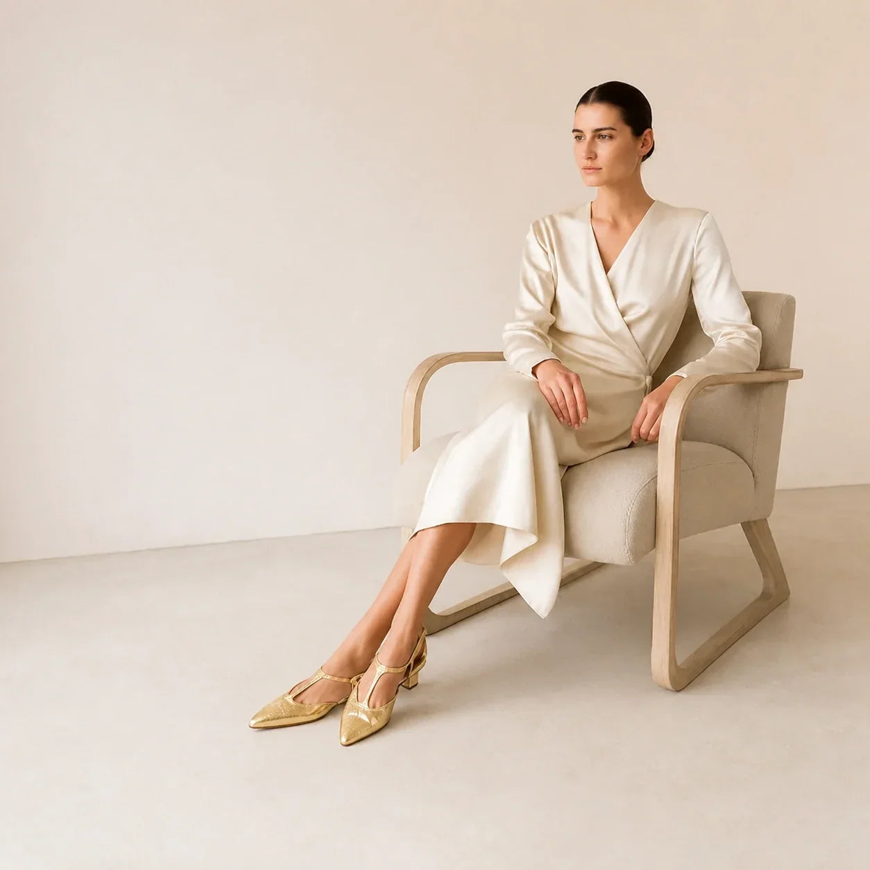 Modelo feminina sentada usando slingback dourado Celeste com os sapatos inteiros visíveis